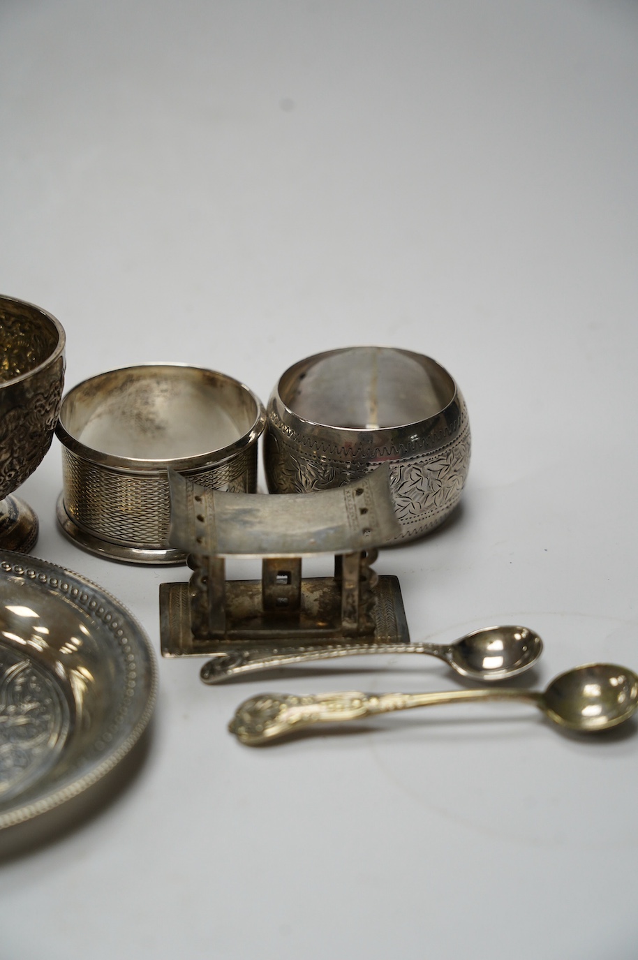 Sundry small silver including five silver napkin rings, and 800 napkin ring, a Victorian silver mustard and salt, an Egyptian small white metal dish, three silver condiment spoons and five plated items. Condition - poor